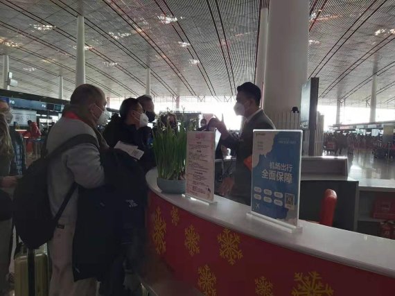 25일 중국 베이징 서우두 공항에서 탑승객들이 마스크를 착용한 채 안내 데스크와 이야기를 나누고 있다./베이징 정지우 특파원