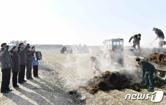 (평양 노동신문=뉴스1) = 화선식 경제선동에 나선 평양시 락랑구역 청년동맹일꾼들. 거름을 나르는 농업 근로자들 옆에서 선전을 펼치고 있다. [국내에서만 사용가능. 재배포 금지. DB 금지. For Use Only in the Republic of Korea. Redistribution Prohibited] rodongphoto@news1.kr