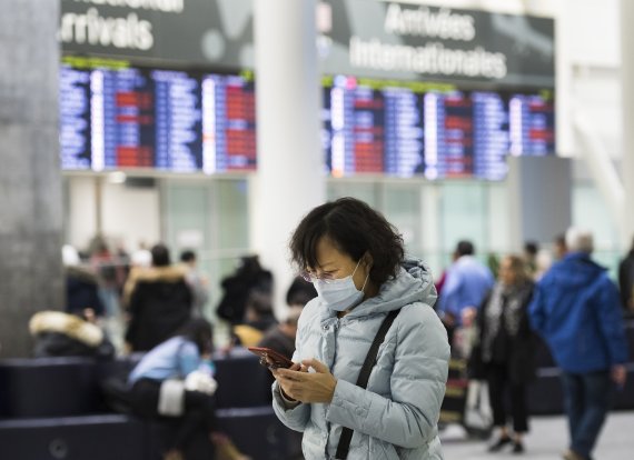 People wear masks following the outbreak of a new virus as people arrive from the International terminal at Toronto Pearson International Airport in Toronto on Saturday, Jan. 25, 2020. A Toronto hospital said Saturday it has a confirmed case of the deadly virus from China, Canada's first. Sunnybrook