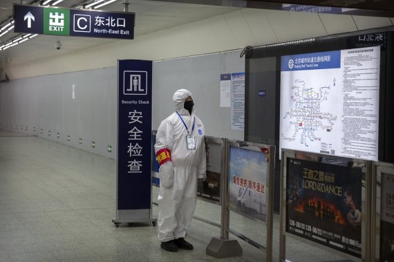 A worker wearing a hazardous materials suit stands at the entrance to a subway station in Beijing, Sunday, Jan. 26, 2020. The new virus accelerated its spread in China, and the U.S. Consulate in the epicenter of the outbreak, the central city of Wuhan, announced Sunday it will evacuate its personnel