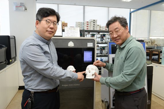 ETRI 전종흥(왼쪽) 박사와 이병남 박사가 3D 프린터를 이용해 의료 시뮬레이션을 위한 머리뼈 모형을 들고 기술을 설명하고 있다. ETRI 제공