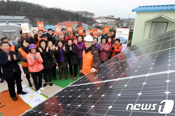 2018년 12월 충북 음성군 봉곡2리 마을 주민들이 태양광 발전설비가 설치된 마을회관 옥상에서 설비를 지원한 기업 관계자와 기념사진 촬영을 하고 있다. © News1