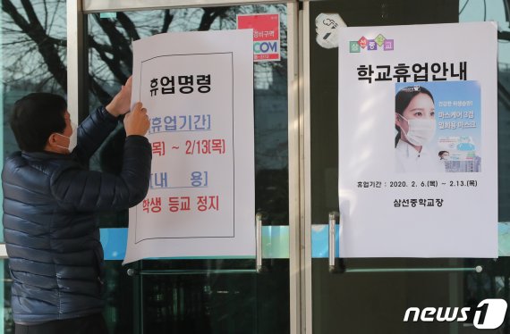 서울시교육청이 서울 중랑구와 성북구에 있는 유치원과 초·중·고교 등 총 42개교에 대해 오는 13일까지 긴급 휴업명령을 내린 6일 서울 성북구 삼선중학교에서 관계자가 휴업을 알리는 안내문을 붙이고 있다. 2020.2.6/뉴스1 © News1 허경 기자