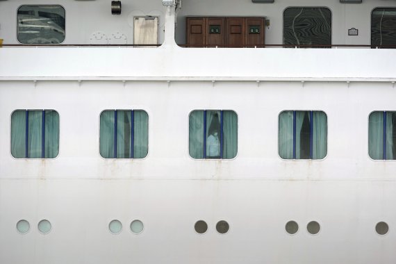 일본 요코하마 항구에 정박하고 있는 크루즈 유람선 다이아몬드 프린세스호에서 7일 격리중인 한 승객이 선실 밖을 내다보고 있다. 일본 정부는 지난 3일 도착한 해당 선박에서 신종 코로나 바이러스 감염증이 발생하자 3700여명의 탑승자 모두에게 잠복기가 끝나는 14일간 선박에 머무르라고 지시했다. AP 뉴시스