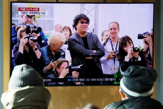 People watch a TV broadcasting a news report on South Korean director Bong Joon-ho who won four Oscars with his film 'Parasite', in Seoul, South Korea, February 10, 2020. REUTERS/Heo Ran /REUTERS/뉴스1 /사진=