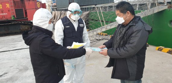 포항해양경찰서 직원들이 중국인 선원(오른쪽)에게 마스크 및 중국어 교육자료를 전달하고 있다.