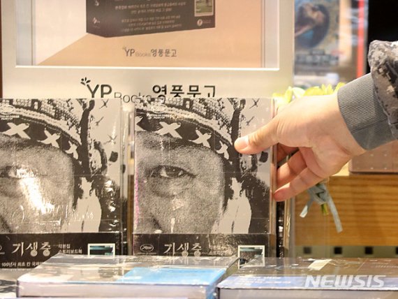 [서울=뉴시스]박주성 기자 = 영화 '기생충'이 2020년 제92회 아카데미 시상식 4관왕 쾌거를 이룬 가운데 11일 오후 서울 용산구 한 대형 쇼핑몰 서점에서 시민이 '기생충' 각본집&스토리북 세트를 고르고 있다. 봉준호 감독이 직접 쓰고 그린 각본집과 스토리보드북의판매량이 수상 전날(9일) 대비 20배 이상 올랐고 인터넷 서점 예스24에서는 11일 베스트셀러 차트 10위에 올랐다. 2020.02.11. park7691@newsis.com
