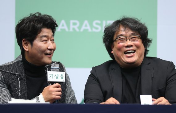 봉준호 감독(오른쪽)이 19일 서울 소공로 웨스틴조선호텔에서 열린 영화 '기생충' 기자회견에서 배우 송강호의 답변에 밝게 웃고 있다. 뉴시스