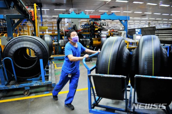 [칭다오=AP/뉴시스] 24일(현지시간) 중국 산둥성 칭다오시에 위치한 공장에서 마스크를 낀 노동자가 제조된 타이어를 옮기고 있다. 2020.02.28.