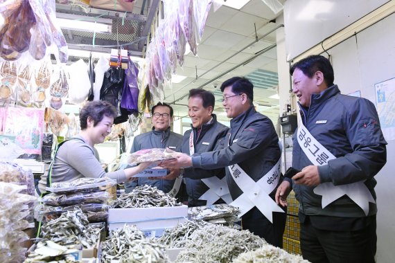 김지완 BNK금융그룹 회장(왼쪽 세번째), 빈대인 BNK부산은행장(왼쪽 네번째), 성명환 BNK저축은행 대표이사(왼쪽 다섯번째), 이두호 BNK캐피탈 대표이사(왼쪽 두번째)가 지난달 17일 부산 자갈치시장에서 진행한 전통시장 활성화 캠페인에 참여해 상인들과 만나 이야기를 나누고 있다(왼쪽 사진). BNK금융 제공