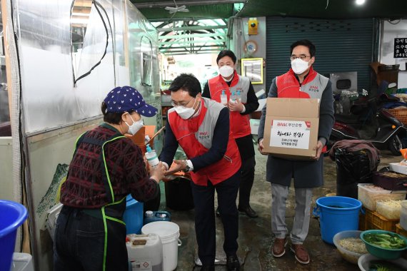 BNK부산은행 직원들이 지난달 28일 부산 연제구 전통시장을 방문해 시장 상인들에게 마스크와 손 세정제를 전달하고 있다. BNK금융 제공