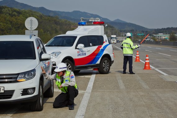 안전순찰원이 갓길에 세워진 차량을 점검하는 모습. 또다른 안전순찰원은 주변 차량을 통제하고 있다. 한국도로공사 제공