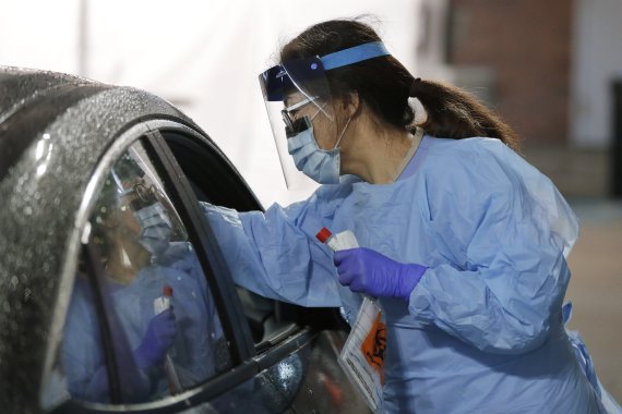 A nurse at a drive-up coronavirus testing station set up by the University of Washington Medical Center uses a swab to take a sample from the nose of a person in a car Friday, March 13, 2020, in Seattle. UW Medicine is conducting drive-thru testing in a hospital parking garage and has screened hundr