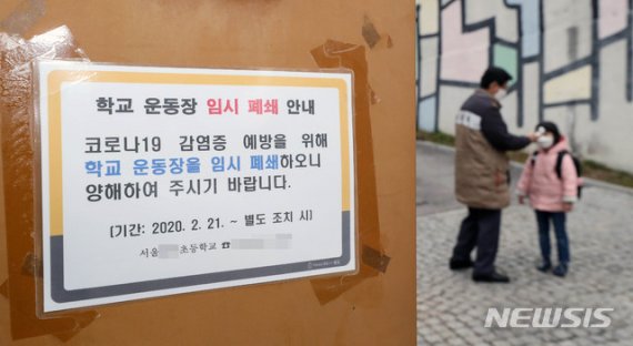 개학 연기 발표가 예정된 17일 오전 서울 종로구 한 초등학교에서 긴급돌봄 참여 학생이 등교하며 체온을 측정하고 있다. 뉴시스