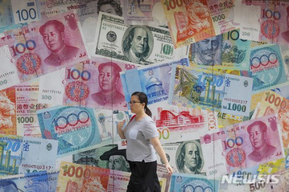 【홍콩=AP/뉴시스】지난해 8월6일(현지시간) 홍콩에서 한 여성이 달러와 위안화 등으로 장식된 환전소 앞을 지나고 있다. 2020.03.19.
