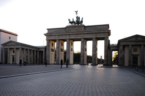 Only few people gather in front of the Brandenburg Gate on the nearly empty Pariser Platz in Berlin, Germany, Saturday, March 21, 2020. In order to slow down the spread of the coronavirus, the German government has considerably restricted public life and asked the citizens to stay at home. For some 
