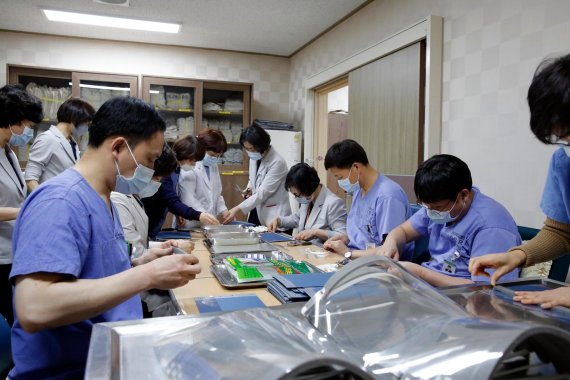 전남대병원 간호사와 행정직원 등 병원 관계자들이 코로나19 감염 확산으로 물량이 부족한 의료인 감염방지용 안면보호대인 '페이스 쉴드'를 직접 제작하고 있다.사진=전남대병원 제공