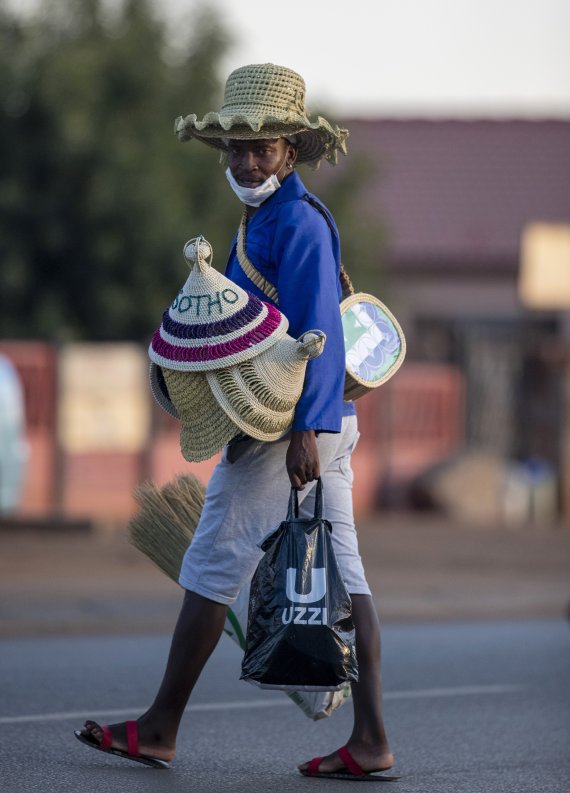 남아프리카 요하네스버그 인근 데비톤에서 24일(현지시간) 전통모자와 마스크를 착용한 시민이 거리를 지나고 있다.AP뉴시스