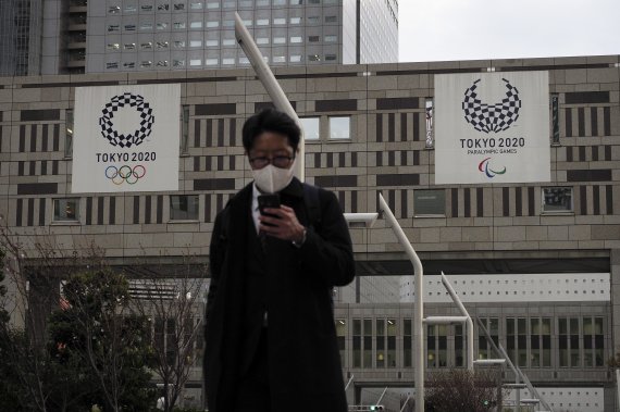 도쿄 신주쿠 소재 도쿄도청 앞에서 마스크를 쓴 남성이 스마트폰을 보면서 길을 걷고 있다. AP뉴시스