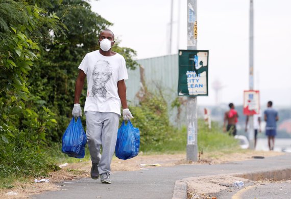 남아프리카공화국의 더반 인근 움라지 마을에서 지난달 31일(현지시간) 한 주민이 마을 봉쇄 와중에 생필품을 옮기고 있다. 남아공 정부는 지난달 26일부터 코로나19 확산 방지를 위해 21일간의 전국 단위 봉쇄령을 내렸다.로이터뉴스1