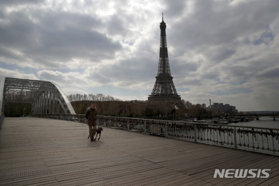 [파리=AP/뉴시스]2일(현지시간) 신종 코로나바이러스 감염증(코로나19)이 확산하고 있는 프랑스 파리 드빌리 인도교에서 한 남성이 개와 걷고 있다. 뒤쪽으로는 에펠탑이 보인다. 2020.04.03. /사진=뉴시스