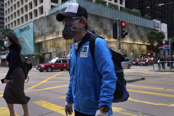 People wearing face masks walk at a downtown street in Hong Kong Monday, April 6, 2020. The new coronavirus causes mild or moderate symptoms for most people, but for some, especially older adults and people with existing health problems, it can cause more severe illness or death. (AP Photo/Vincent Y