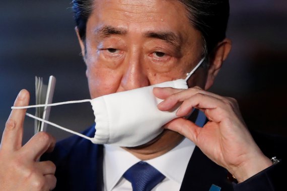 아베 신조 일본 총리가 6일 총리관저에서 긴급사태 선언과 관련한 기자들의 질문에 답하기 위해 마스크를 벗고 있다. 로이터 뉴스1