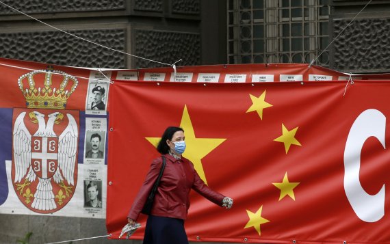 지난 13일 세르비아 베오그라드에서 마스크를 쓴 시민이 중국 국기가 그려진 현수막 앞을 지나고 있다.AP뉴시스