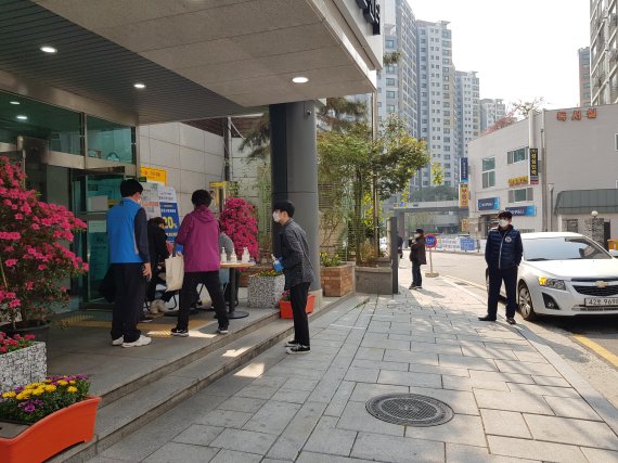 15일 오전 서울 종로구 교남동 주민센터 앞에서 시민들이 투표하기에 앞서 손소독제를 뿌리고 있다. /사진=윤홍집 기자