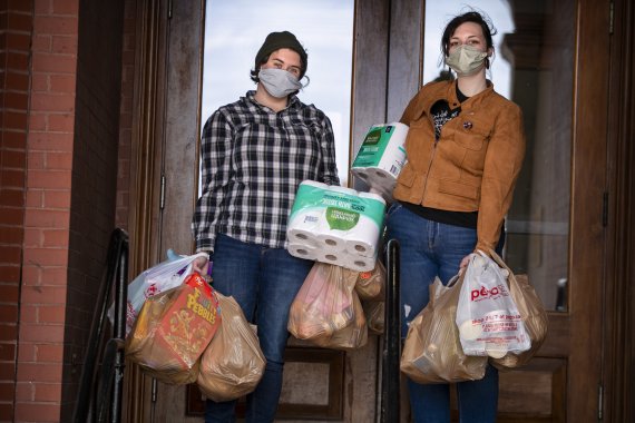 Alex Campbell, left, and Sasha Leppanen return to their apartment building after a successful trip to the grocery store that included the purchase of hard-to-find toilet paper, Tuesday, April 21, 2020, in Portland, Maine. Toilet paper has been made scarce in stores since the outbreak of the coronavi