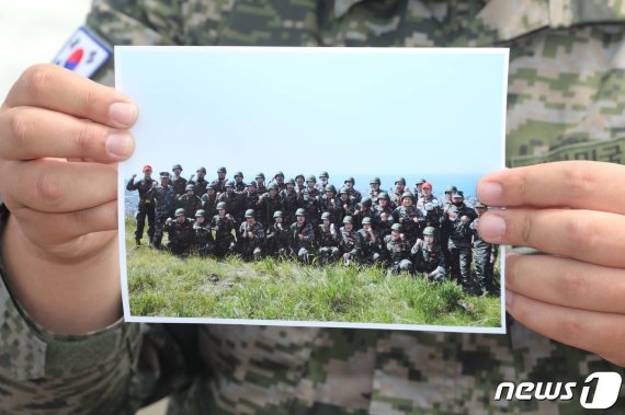 한국 축구 대표팀 에이스 손흥민(28·토트넘)이 제주 서귀포시 대정읍 해병대 9여단 훈련소에서 기초군사훈련을 마치고 퇴소한 8일 오전 손흥민의 훈련소 동기가 함께 찍은 사진을 들고 있다.2020.5.8/뉴스1 © News1 오현지 기자