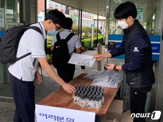 고등학교 3학년 등교 개학 첫날 삼일공업고등학교 정문 앞에 대기 중인 한 교사가 화학공업과 교사들이 직접 만든 손소독제를 학생들에게 나눠 주고 있다. 이윤희 기자 © 뉴스1