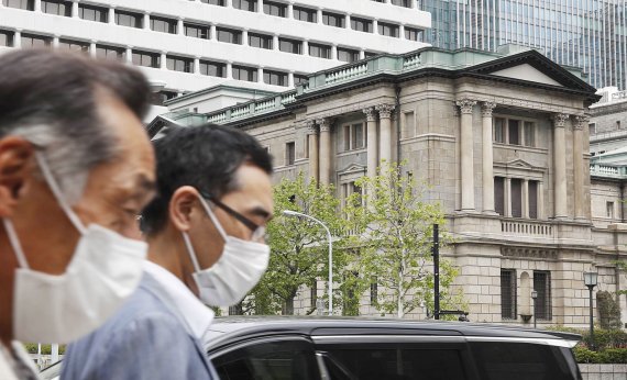일본 도쿄의 일본은행(BOJ)본부 앞으로 마스크를 쓴 사람들이 길을 지나고 있다. AP뉴시스