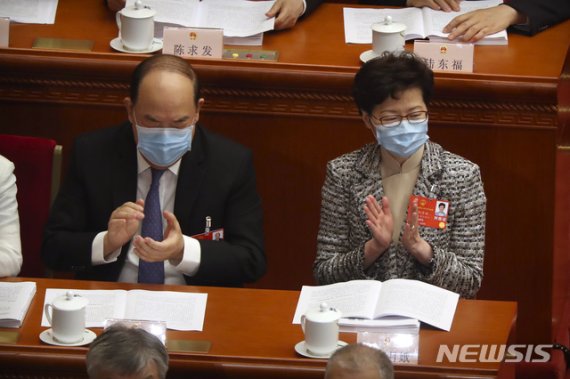 [베이징=AP/뉴시스]지난 22일(현지시간) 중국 베이징 인민대회당에서 중국 최대 정치 행사인 전국인민대표회의(전인대)가 열리고 있는 가운데 캐리 람 홍콩 행정장관(오른쪽)이 신종 코로나바이러스 감염증(코로나19)을 막기 위해 마스크를 쓴 채 박수를 치고 있다. 뉴시스.