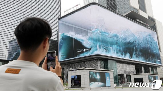 최근 서울 강남구 삼성동 코엑스 앞 '파도'가 전 세계적인 관심을 끌며 한국의 초대형 사이니지 기술력이 새삼 조명받고 있다. 이 전광판은 삼성전자가 2018년 3월 22일 CJ파워캐스트, 한국무역협회와 공동으로 설치한 것이다. 25일 오후 서울 강남구 코엑스 앞을 지나던 시민이 전광판에서 몰아치는 입체 파도 'Wave'를 스마트폰에 담고 있다. 2020.5.25/뉴스1 © News1 박지혜 기자