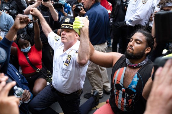 1일(현지시간) 미국 뉴욕에서 조지 플로이드의 죽음에 항의하는 시위대가 시위를 잠시 멈춘 사이 테렌스 모나한 뉴욕시 경찰서장이 한 운동가와 함께 무릎을 꿇고 손을 맞잡고 있다. AP뉴시스