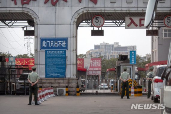 [베이징=AP/뉴시스]중국 베이징 공안이 13일 코로나19의 새로운 진원지로 떠오른 베이징 신파디 농산물 도매시장 입구에 바리케이드를 친 채 경계를 서고 있다.