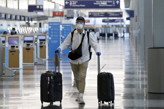 코로나19가 대유행하던 지난 2020년 6월16일(현지시간) 미국 시카고의 오헤어 국제공항에서 마스크와 보호경을 착용한 승객이 터미널을 걷고 있다.AP뉴시스