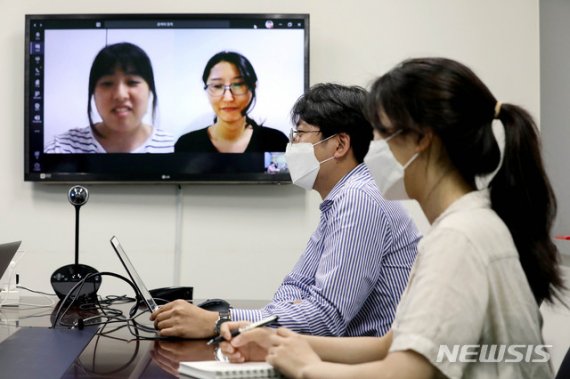 지난달 서울 금천구 인프라웨어 회의실에서 직원들이 코로나19 예방을 위해 재택근무하는 직원들과 화상회의를 하고 있다. 뉴시스 제공