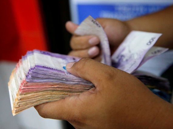 필리핀 페소화가 경기침체 속에 올해 미국 달러에 대해 4% 가치가 급등했다. 2018년 9월 19일(현지시간) 마닐라에서 한 남성이 페소 뭉치를 들고 돈을 세고 있다. 로이터뉴스1