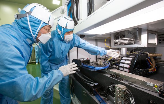 삼성전자 직원이 레이저 설비 협력사인 이오테크닉스 직원과 양사가 공동 개발한 반도체 레이저 설비를 살펴보고 있다. /삼성전자 제공