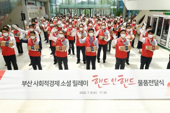 BNK부산은행은 8일 오전 부산 사회적경제기업이 생산한 '핸드 인 핸드' 물품을 본점 인근 저소득 가구에 전달하는 임직원 봉사활동을 펼쳤다. 물품 전달식에 참석한 빈대인 부산은행장(앞줄 오른쪽 세번째) 등 임직원들이 기념사진을 찍고 있다./제공=부산은행