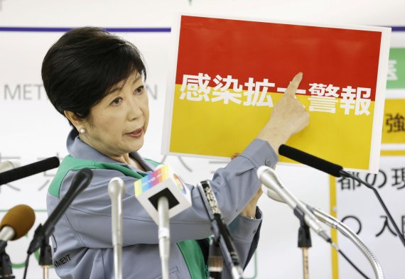 고이케 유리코 도쿄도지사가 지난 15일 기자회견을 열어 '감염 확대 경보'라고 적힌 팻말을 들어올리고 있다. 로이터 뉴스1