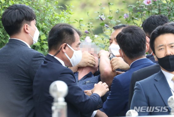 경호원들이 16일 오후 서울 여의도 국회에서 열린 제21대 국회 개원식에 참석해 개원 축하 연설을 마친 문재인 대통령을 향해 신발을 던지고 돌발 발언을 한 시민의 입을 막고 있다.