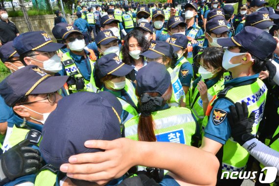 김소영 사용후핵연료 관리정책 재검토위원장이 24일 오전 경북 경주시 감포읍 복지회관에서 경찰의 보호를 받으며 발표회장을 빠져나고 있다. 이 곳에서 열릴 예정이던 월성월성 원자력발전소 임시저장시설(맥스터) 증설에 대한 지역 의견수렴 결과 발표가 반대 단체의 반발로 무산됐다. 뉴스1