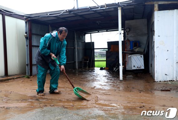 강원 강릉시 옥계면 주수리의 한 주택이 내린 비로 침수돼 집주인이 토사를 치우고 있다. 뉴스1
