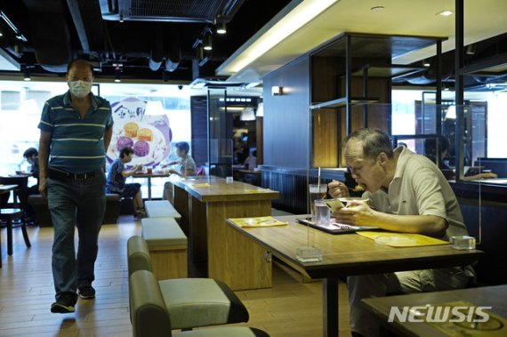 [홍콩=AP/뉴시스]28일 홍콩의 한 칸막이 테이블 식당에서 손님들이 식사하고 있다. 홍콩 정부는 코로나19가 재확산하면서 29일부터 테이크아웃을 제외한 식당 내 영업을 금지하고 모든 공공장소에서의 마스크 착용을 의무화하는 등 강력한 방역 조치를 내놨다.