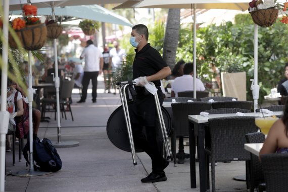 지나날 12일(현지시간) 미국 플로리다주 마이애미비치의 한 음식점에서 종업원이 마스크와 장갑을 착용한채 근무하고 있다.AP뉴시스