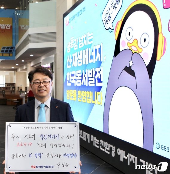 : 박일준 동서발전 사장이 울산 본사 사옥 1층 로비에 설치된 LED 전광판 앞에서 코로나19 극복 메시지를 담은 피켓(손팻말)을 들고 사진을 촬영하고 있다. (동서발전 제공) © 뉴스1