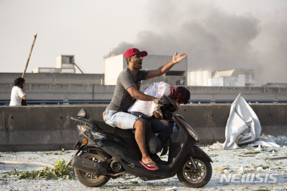 레바논 베이루트에서 4일(현지시간) 대폭발이 발생한 후 한 남성이 오토바이에 부상자를 태운채 다급한듯 소리를 치고 있다.AP뉴시스
